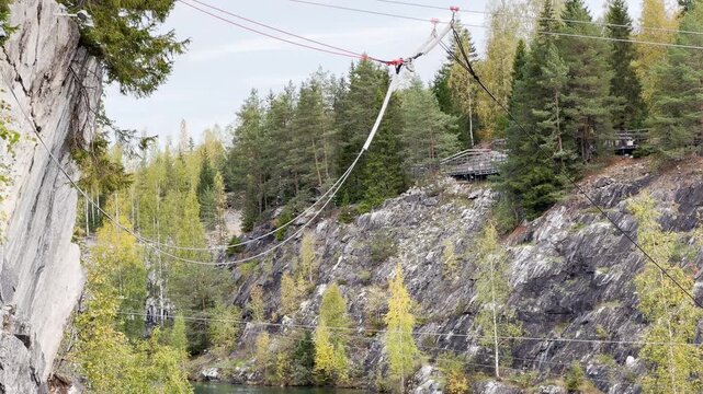 Zipline cables stretch over a calm marble canyon lake in Ruskeala, Karelia. Golden trees reflect on the quiet water. The scenic landscape brings a peaceful and adventurous feeling.