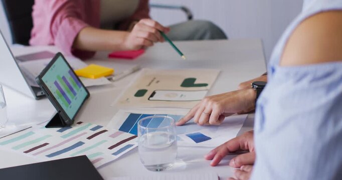 Green pencil is reaching at table, pointing mockup as right hand is aligning swatches during review