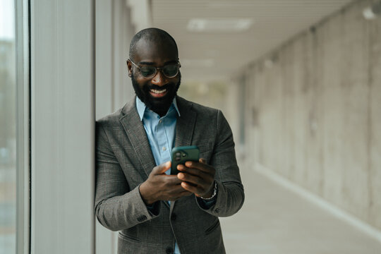 Black businessman smiling and using smartphone for communication