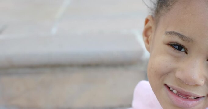 African American girl after cue smiling shifting toward lens on stone steps pink hoodie, copy space