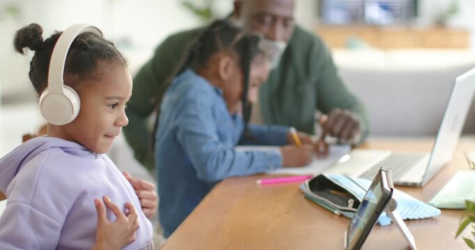 African American family guiding girls at table, mature man pointing at paper, tablet causing smiles
