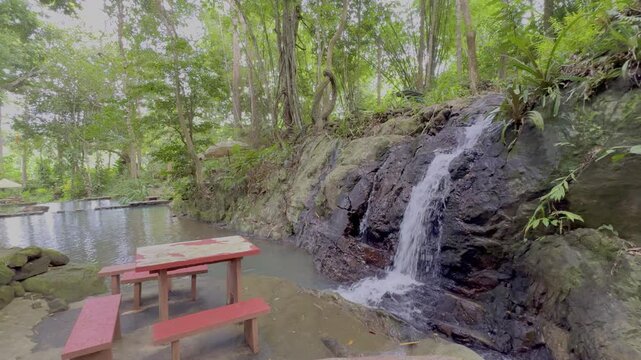 Kathu Dam waterfall water gently flowing down the rocks surrounded by lush green trees flowers and tables Patong on the Island of Phuket Thailand
