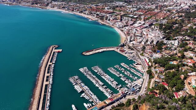 Aerial view of Javea marina on the Costa Blanca, Spain, showing rows of moored yachts, turquoise Mediterranean waters, sandy beach and the residential town spreading inland