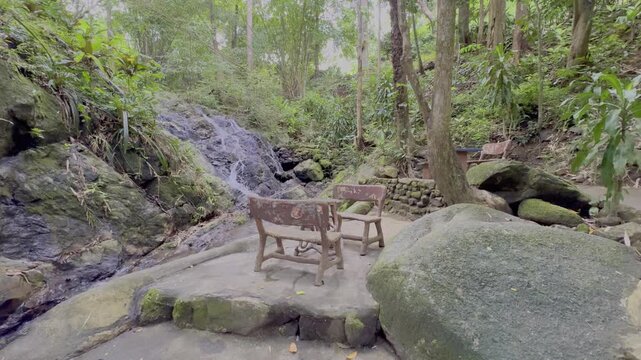 Kathu Dam waterfall water gently flowing down the rocks surrounded by lush green trees flowers and tables Patong on the Island of Phuket Thailand