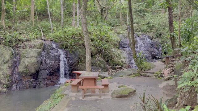 Kathu Dam waterfall water gently flowing down the rocks surrounded by lush green trees flowers and tables Patong on the Island of Phuket Thailand