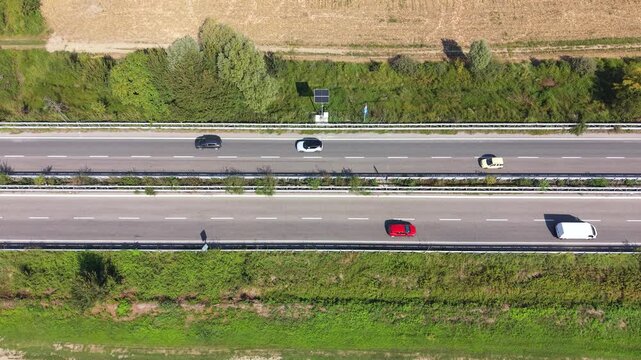 Aerial view of a highway in daylight, with cars moving along the road.
