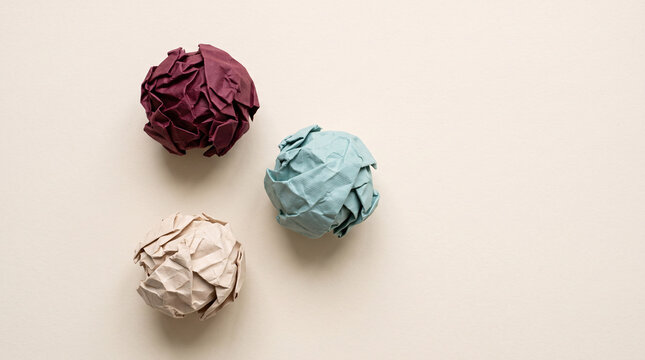 Trois boules de papier froiss&eacute; bordeaux, bleue et beige