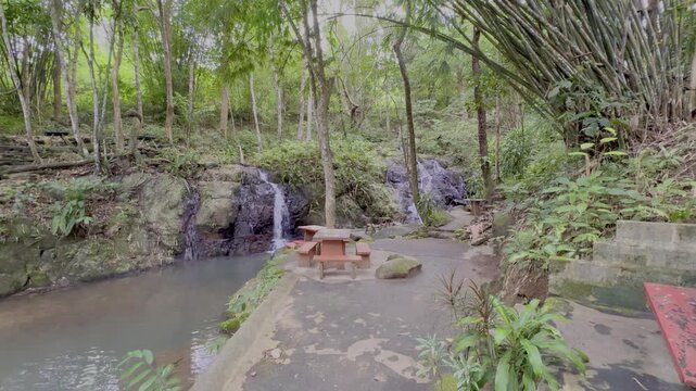 Kathu Dam waterfall water gently flowing down the rocks surrounded by lush green trees flowers and tables Patong on the Island of Phuket Thailand