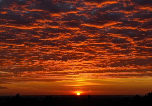 A spectacular and brilliant explosion of warm, fiery colors illuminating the vast evening sky as the sun dips below the distant horizon ,color ,serene ,scenery