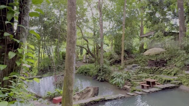 Kathu Dam waterfall water gently flowing down the rocks surrounded by lush green trees flowers and tables Patong on the Island of Phuket Thailand