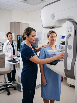 Professional medical technician performing a mammogram screening procedure for a patient in a modern hospital clinic