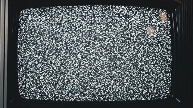 Old television screen with static and horizontal bar during a broadcast interruption in a dark room
