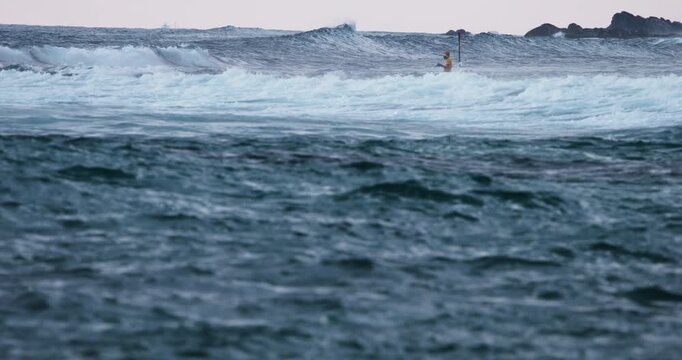 Surfer on the Horizon Amidst Rolling Ocean Waves