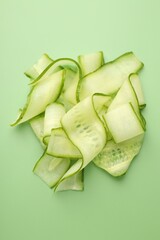 Plakat Slices of ripe cucumber on green background, top view