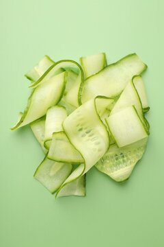 Slices of ripe cucumber on green background, top view