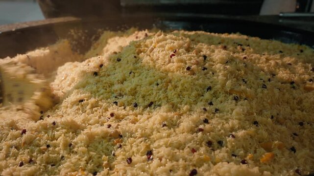 Traditional Uzbek wedding plov is prepared in a huge kazan as the seasoned rice is carefully mixed. Authentic national cuisine, Uzbekistan's traditions, festive hospitality, gastronomic tourism