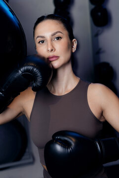 Confident young caucasian female boxer in gym with boxing gloves