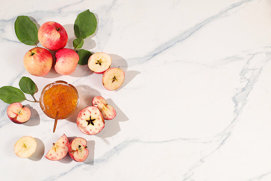 Fresh apple butter or jam made from light colored apple varieties. Jars of preserves, fruit butter, and fruit pur es arranged on a concrete kitchen countertop. Concept of homemade preserves, banner