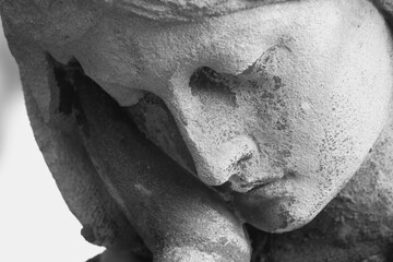 Obraz premium Close-up of a sorrowful angel statue resting its face on a hand, symbolic image of grief, mourning, loss, loneliness and remembrance.