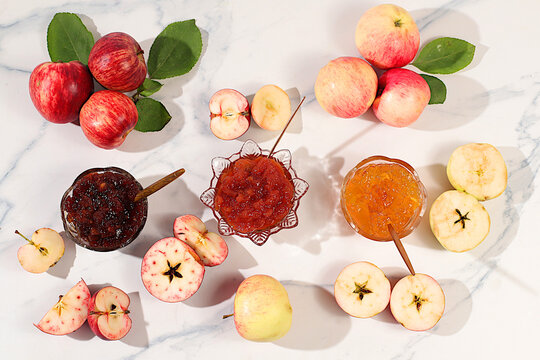 Fresh apple butter or jam made from various apple varieties. An assortment of preserves, fruit butters and fresh fruit purees arranged on a concrete kitchen counter.home canning concept, banner