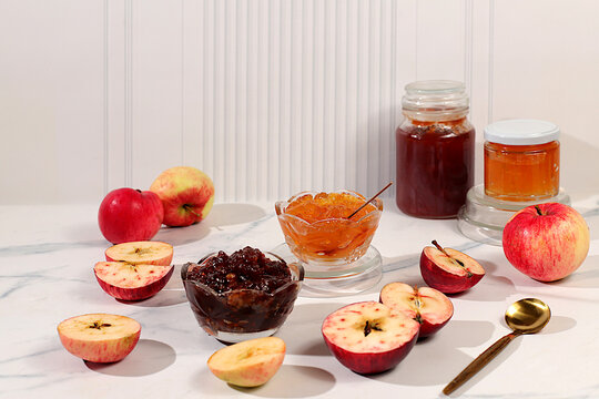 An assortment of preserves, fruit butters and fresh fruit purees arranged on a concrete kitchen counter.Fresh apple butter or jam made from various apple varieties. home canning concept, banner