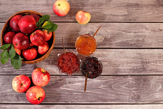 An assortment of preserves, fruit butters and fresh fruit purees arranged on wooden kitchen counter.Fresh apple butter or jam made from various apple varieties. home canning concept, banner