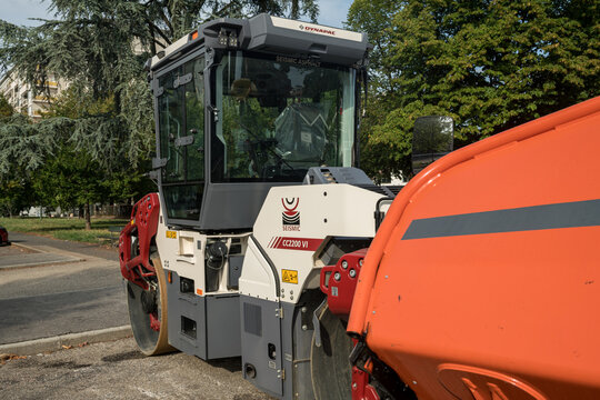 Heavy road roller compactor flattening fresh asphalt layer on urban street, industrial construction machinery resurfacing road, maintenance work site top high angle view, Turin, Italy, August 28, 2026