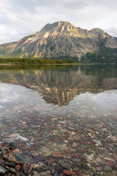 multi-coloured pebbles at driftwood beach in Waterton Lakes National Park Alberta Canada with mountain reflecting on lake