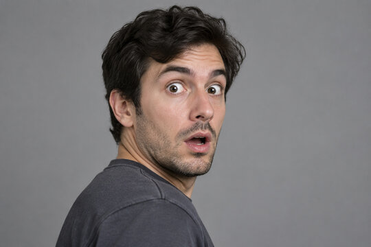 Surprised adult with wide eyes on gray background, shock and unexpected news concept