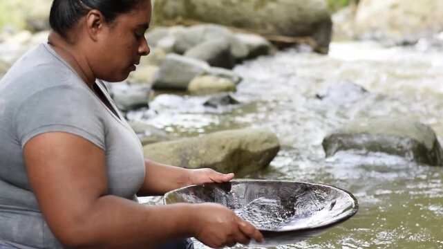 Latin American woman removing the last sediment from a batea to check for gold