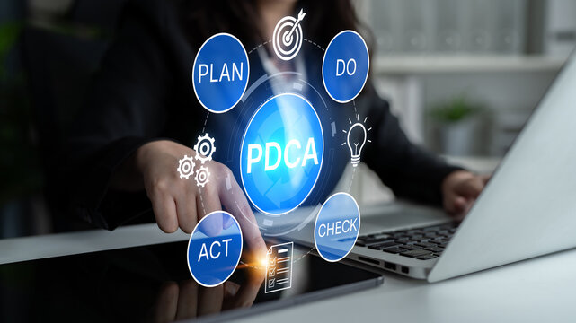 Conceptual representation of PDCA cycle with businesswoman interacting with modern technology and strategic planning elements in a professional office setting. Bitwise.