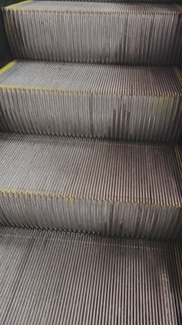 Empty metal escalator steps moving up. Abstract background of mechanical stairs in a subway, airport, or shopping mall. Endless motion loop