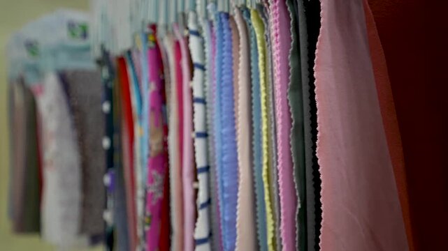 Rows of colorful fabric swatches with labeled tags hang on a display rack