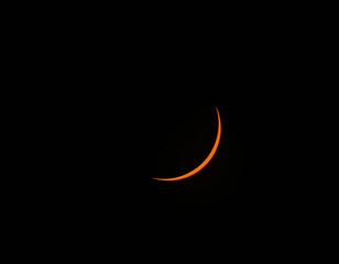 A thin orange crescent moon glows against the dark night sky. © Kit Leong