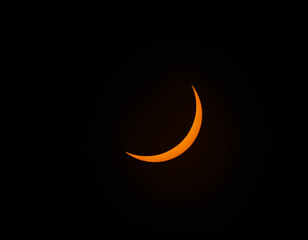 A bright orange crescent moon glows against a pitch black sky. © Kit Leong