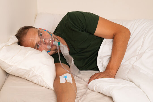 Sick Man Receiving Oxygen and Intravenous Therapy While Lying in Bed
