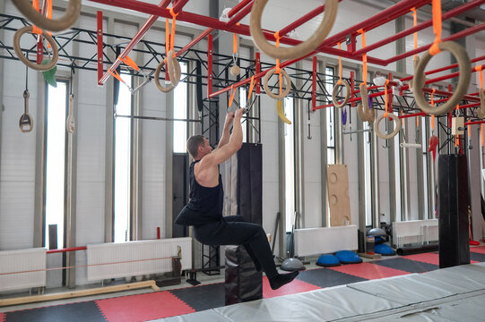 An athletic man practices at a ninja club's indoor obstacle course.