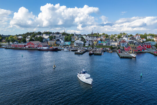 View across the harbor of Lunenburg, Nova Scotia, featuring colorful houses, historic ships, and boats beneath dramatic clouds