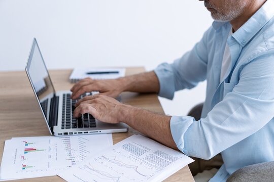 Portrait of happy 40s freelancer man sitting at desk with laptop computer at home office