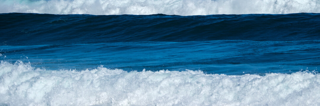 Layered Blue Ocean Waves and White Sea Foam in Panoramic View