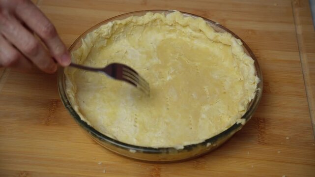 Pricking pastry dough with a fork. Hands prick the pastry dough with a fork before baking.