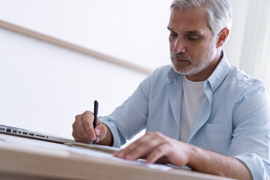 40s business man company manager investor working on computer writing notes