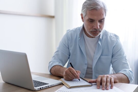 40s business man company manager investor working on computer writing notes