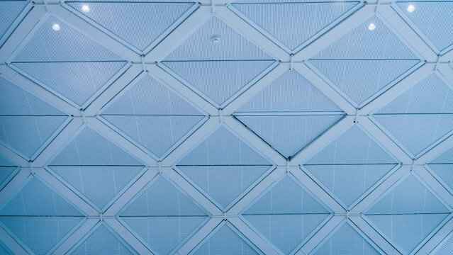 Modern geometric ceiling structure with white triangular panels and metal grid. Architecture interior. Real Photo