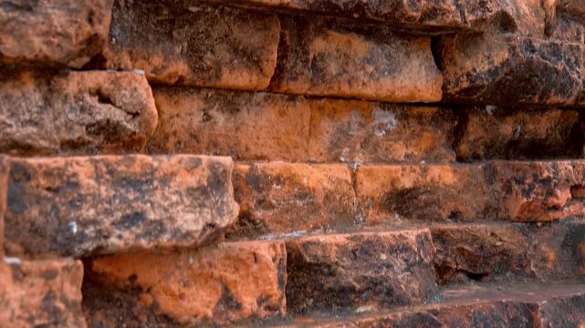 The weathered, coarse texture of an ancient reddish-orange brick or laterite stone wall of Po Nagar Temple Tower in Nha Trang, Vietnam. Closeup. Shot in motion