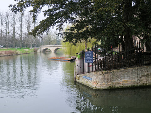 Punting in Cambridge on the River Cam. Visitors and Students enjoy a trip in the Spring on a grey cloudy spring day.