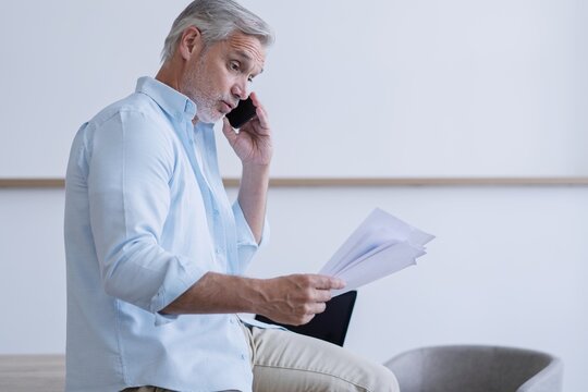 Busy mature business man talking on mobile phone in office