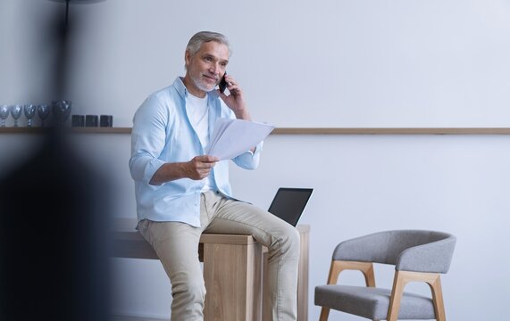 Busy mature business man talking on mobile phone in office