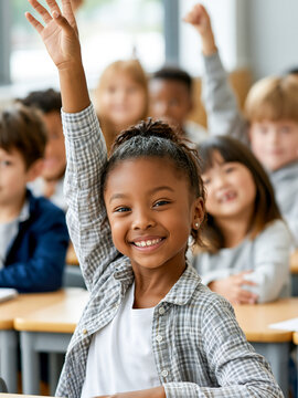 Close up of a smiling African American schoolgirl raising her hand in a diverse classroom, eager to answer a question during an engaging lesson at an elementary school.