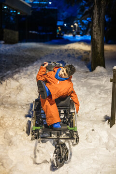 Young boy experiencing winter snow in wheelchair